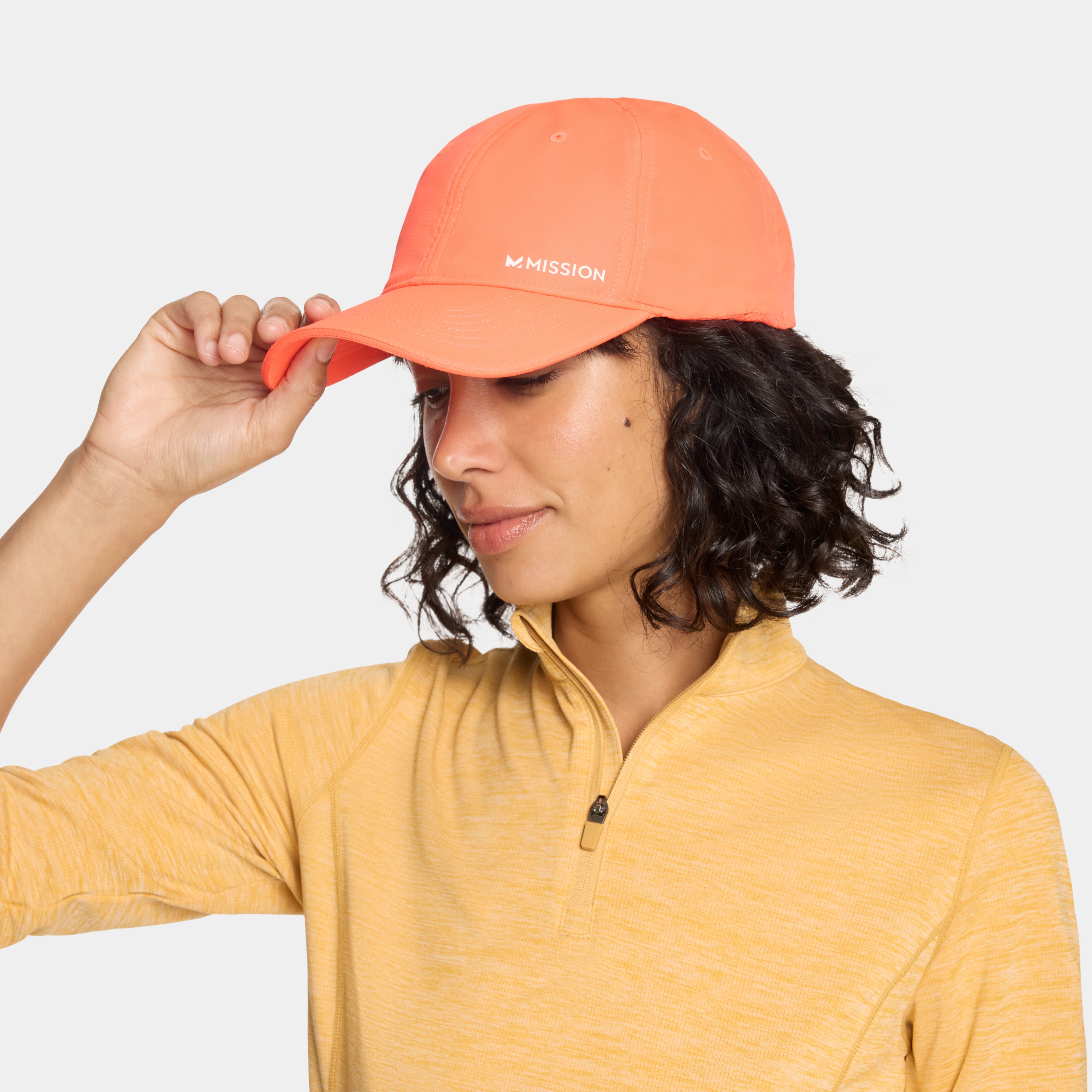 Person wearing an orange cap with 'Mission' branding on a plain background