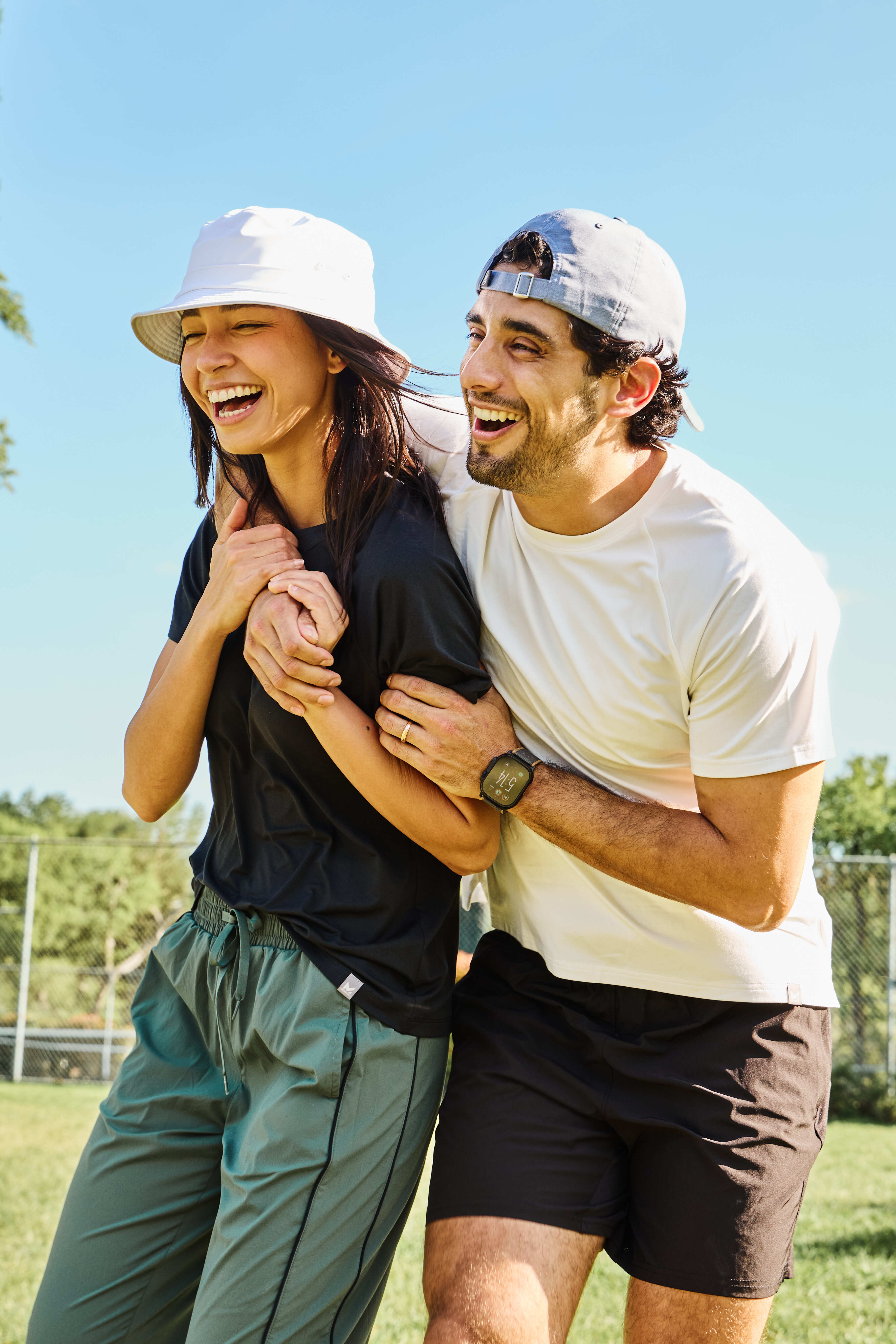 Two people laughing together outdoors on a sunny day wearing Missions new all day cooling items