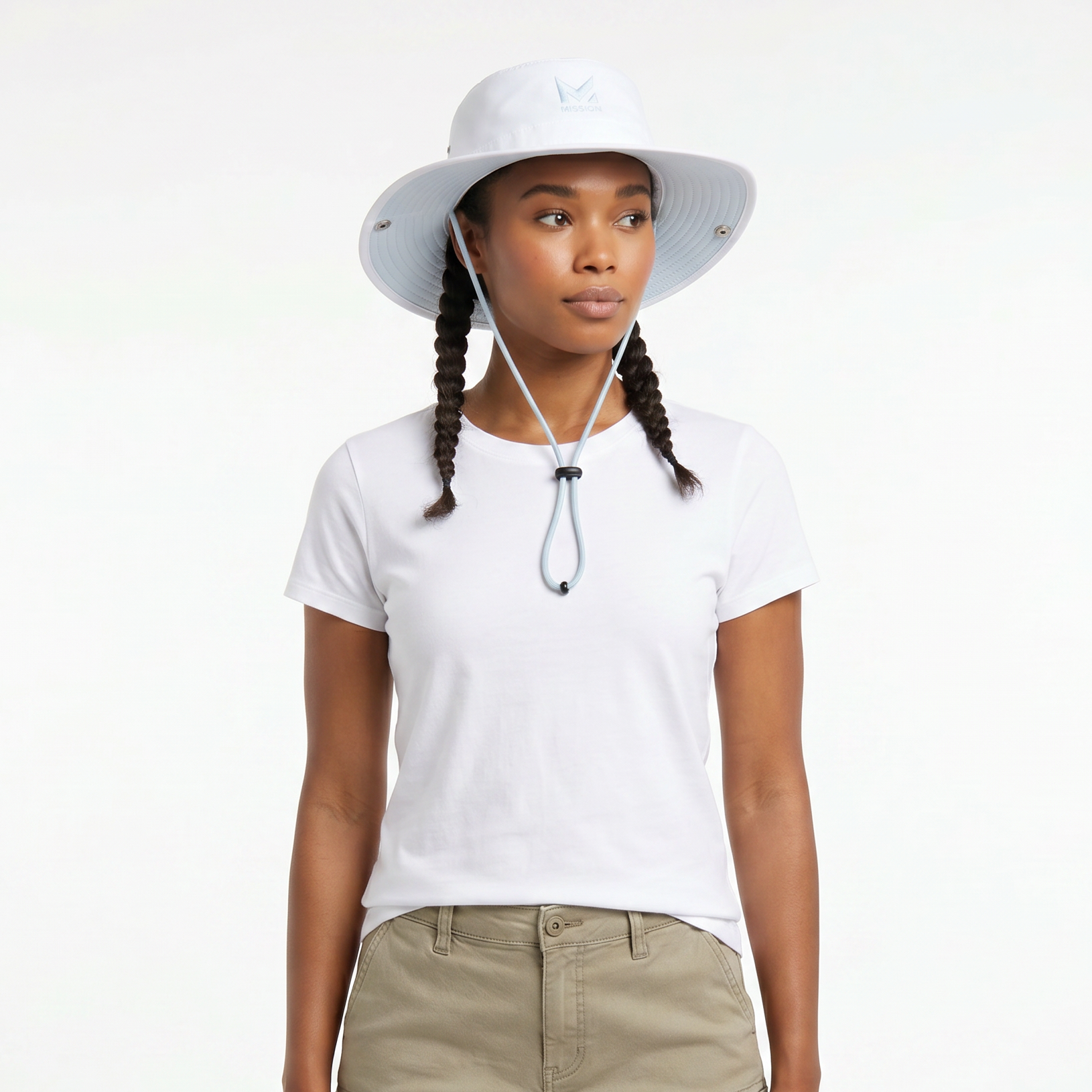 A woman wearing a white wide-brim sun hat with a chin strap, a white short-sleeve t-shirt, and khaki pants, photographed against a clean white studio background.