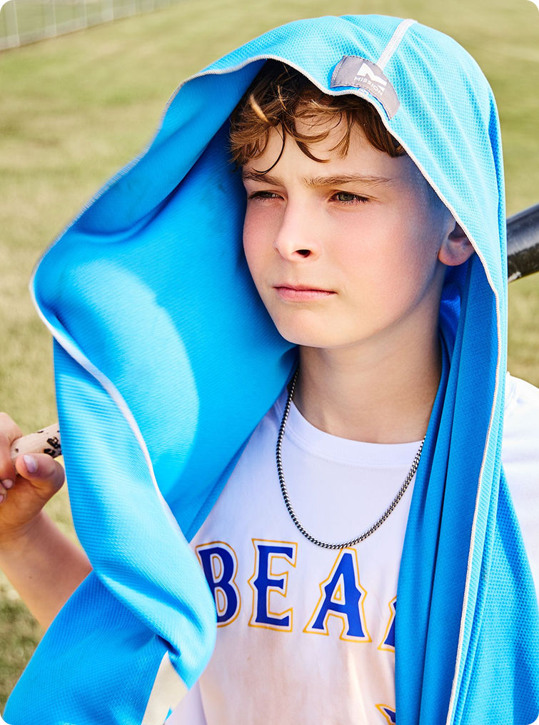 A young boy wearing a bright blue athletic hoodie with a white t-shirt underneath, standing outdoors on a grassy field.