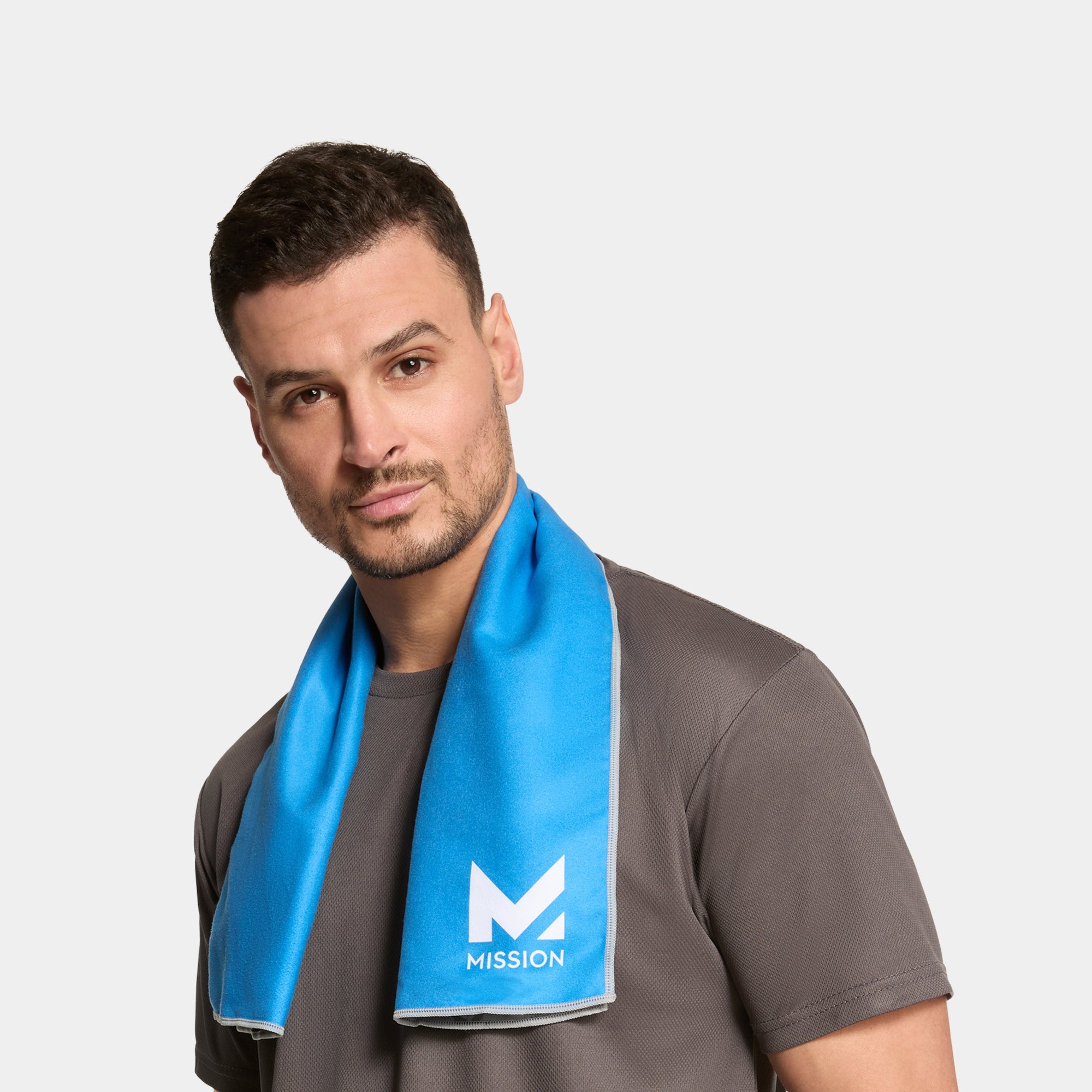 Man wearing a blue towel with 'Mission' logo around his neck on a gray background