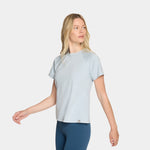 Woman wearing a light gray t-shirt and blue leggings on a white background