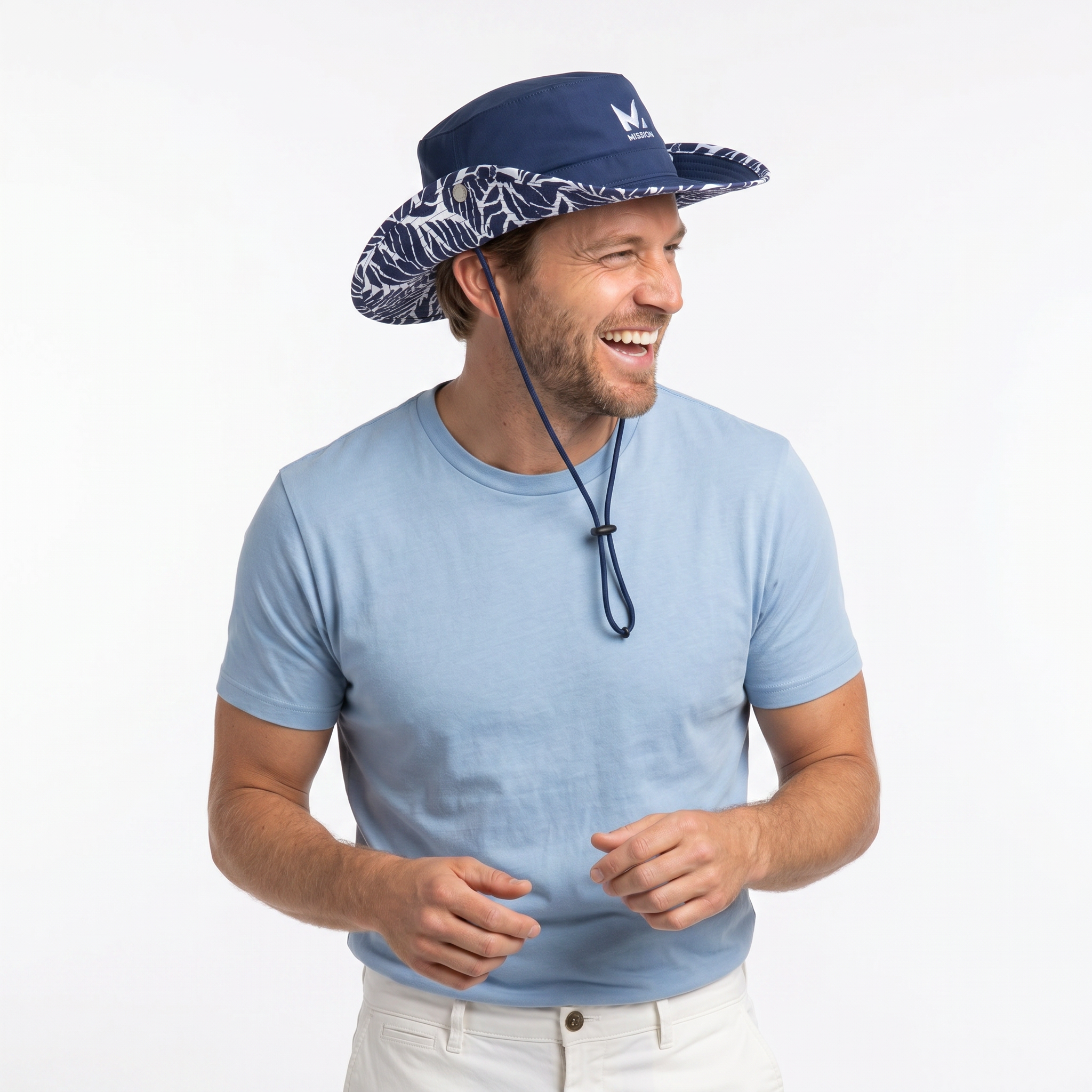 A man wearing a navy blue wide-brim sun hat with a white abstract pattern on the brim and a matching chin strap, paired with a light blue t-shirt and off-white pants, set against a plain white background.